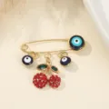 Broche cerise œil maléfique, métal doré avec strass rouges et perles Nazar bleues. - Style Cerise / 3.8x2.8cm