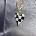 Close-up detail of a chic black and white checkered heart pendant keychain and bag charm. - Style K