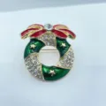 Nahaufnahme Detail der funkelnden Strasssteine und Emaillierter Weihnachts-Kranz Brosche. - Tropföl-Finish