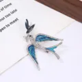Close-up of a vintage blue enamel flying bird brooch with sparkling rhinestones and metal. - Blue Swallow