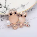 Dettaglio squisito della spilla a doppio gufo, lega oro rosa con strass scintillanti e perla. - Stile Gufi Doppi (0401-03)
