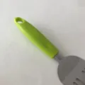 Détail de spatule en acier inoxydable avec poignée ergonomique verte et structure en métal. - Style à Poignée Verte