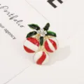 Gedetailleerde close-up van de metalen kersenbroche en servettenring met emaille en strass. - Kerstbes