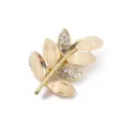 Nahaufnahme der eleganten Goldblatt-Brosche, verziert mit schimmernden Katzenaugen und Strasssteinen. - Strass Blatt