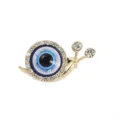 Nahaufnahme Detail einer vergoldeten Schneckenbrosche mit funkelndem Strass-Auge und Motiv. - Schnecke des Bösen Blicks