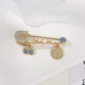 Dettaglio della spilla di sicurezza dorata con malocchio turco e strass brillanti - Mix Blu Chiaro