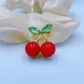 Close up shot of a cute cherry brooch with red beads and green crystal leaves on satin. - Light Green Crystal