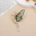 Dettaglio spilla a farfalla verde con strass scintillanti e un elegante ciondolo floreale raffinato. - Farfalla con Nappina