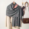 Close-up of a cozy grey winter scarf featuring cute pink heart prints and fringe details. - Small Heart Pattern - Gray