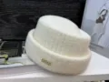 Nahaufnahme Detail der warmen Winter Strickmütze in Cremeweiß mit Kristall Buchstaben Dekor. - Milchweiß