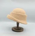 Détail rapproché d'un élégant chapeau cloche en laine à bord roulé avec accent métallique. - Chameau
