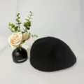 Schwarze Strickbaret Detailansicht, klassischer Retro-Stil, weiche Textur aus Stoff. - Schwarz