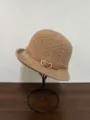 Détail chapeau bob effet laine marron, avec lanière en cuir et boucle dorée élégante. - Café