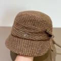 Nahaufnahme des braunen Tweed-Eimerhuts mit schicker Schleife und metallenem Logo-Pin. - M (56-58cm) / Orange Kaffee Karo