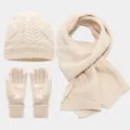 Vista detallada de la textura suave y el tejido del conjunto de gorro bufanda y guantes de punto. - Beige