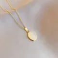 Detailed close-up of gold stainless steel necklace with oval white cat eye stone pendant. - White Cat's Eye Stone / Gold