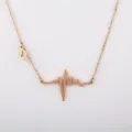 Nahaufnahme einer roségoldenen EKG Herzschlag Halskette mit Herzanhänger aus Titanstahl Schmuck. - EKG Puls Wellenform Stil / Roségold