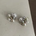 Gedetailleerde close-up van onregelmatige oorbellen met parels en metalen kralen. - Pareloorbellen