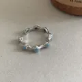 Silberner offener Ring mit blauen Steinen, zartes geflochtenes Spitzenblumen-Design, einstellbar. - R705-A (Blauer Strass)