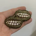 Gedetailleerde close-up van lippenvormige strass en parel oorbellen, gouden metaal. - Zwarte Lippen