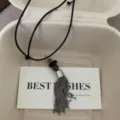 Gedetailleerd opname van een unieke metalen kwastketting met decoratieve kralen. - Kwast