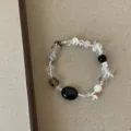 Gedetailleerde close-up van onregelmatige kralenarmband met natuursteen en kristallen. - Zwart Ovaal