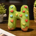 Cute H-shaped letter plush pillow with colorful hearts and donut design for cozy room decor. - Letter H