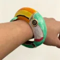 Close-up detailopname van een levendige geëmailleerde papegaai armband om de pols. - Bangle / Groen
