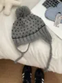 Close-up detail of the grey knitted pom-pom hat with earflaps and cute heart patterns. - Heart Jacquard Pom Pom Style / Light Gray