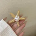Nahaufnahme des goldenen strukturierten Seesterns und Naturmuschelrings für Urlaubs-Stil. - Stil C