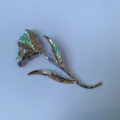 Closeup of silver metal flower brooch with detailed leaf design, stylish and unique accessory. - Silver