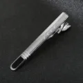 Close-up detail of a sleek silver metal men tie clip with black accent and striped texture. - Style 06