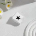 Nahaufnahme des weißen Stoffmanschettenrings mit einem schwarzen gestickten Stern. - Stern Schnalle / Weiß