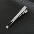 Close-up detail of silver metal tie clip with geometric grid pattern and black inlay. - Style 08