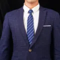 Gros plan d'une veste de costume d'homme texturée bleue avec chemise blanche et cravate. - Style 003