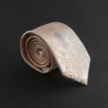 Detailed view of men formal classic champagne gold paisley patterned necktie close-up texture. - Hand-Tied / White Paisley