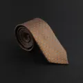 Detailed closeup shot of a rolled men's brown patterned vintage business formal necktie. - Hand-Tied / Polka Dot Floral