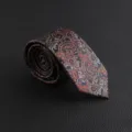 Close-up of vintage paisley patterned men's necktie detail with intricate woven designs. - Hand-Tied / Orange Paisley