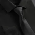 Close-up detail of black mens tie featuring vintage paisley pattern and shirt collar. - Hand-Tied / Black Paisley Print