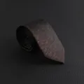 Detailed view of a men's vintage patterned business formal necktie in dark brown textured fabric. - Hand-Tied / Brown Textured