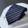 Close-up of a dark blue formal business tie with elegant white and light blue diagonal stripes. - Zipper Style / Blue White Fine Stripe