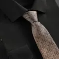 Detailed view of a champagne business necktie with subtle blue dots, paired with a black shirt. - Brown Jacquard Dot Zipper Tie