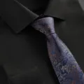 Gros plan d'une cravate d'affaires pour hommes avec motif cachemire et chemise noire soignée. - Cravate à Glissière Paisley Bleu Marine
