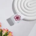 Nahaufnahme einer weißen JK-Marine-Schleife mit zarter rosa Kirschblüten-Stickerei als Detail. - Pflaumenblüte Schnalle / Weiß
