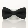 Close-up detail view of classic black men's bow tie with subtle jacquard pattern texture. - Black Paisley Bowtie