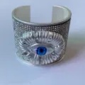 Gedetailleerd overzicht van brede zilveren armband met sprankelende strass-steentjes en blauw oog. - Stijl A (Zilverkleur)