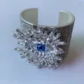 Gedetailleerde close-up van een brede zilveren boze oog-manchetarmband met strass. - Stijl B (Zilver)