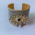 Bracciale rigido aperto placcato in oro con motivo malocchio in strass scintillanti e perle. - Stile C (Oro)