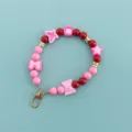 Detailed view of pink and red beaded wristlet strap, cute candy and star charms with gold clasp. - X106-6