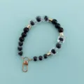 Close-up detail of black and clear crystal beaded phone charm strap with gold lobster clasp. - X105-7 (Black White Classic Heart)